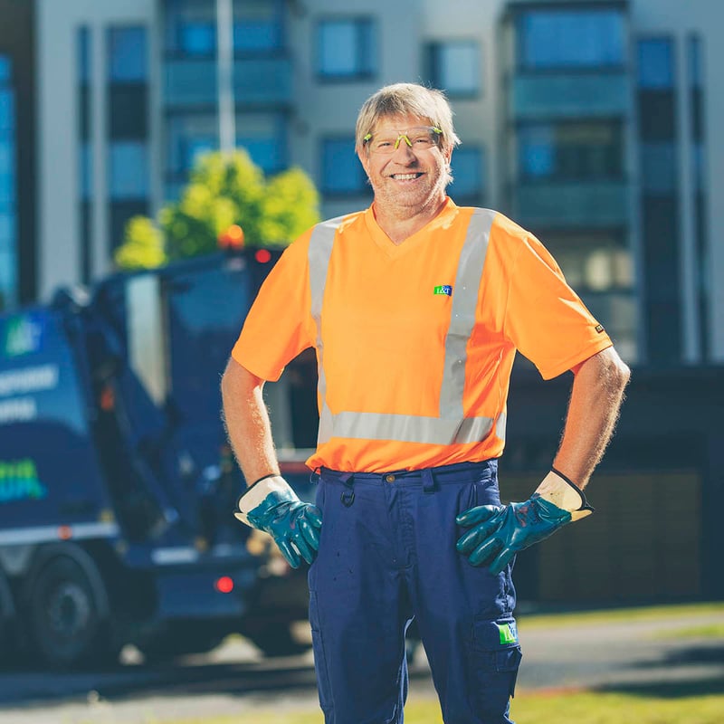 Iäkäs jäteauton kuljettaja hymyilee 