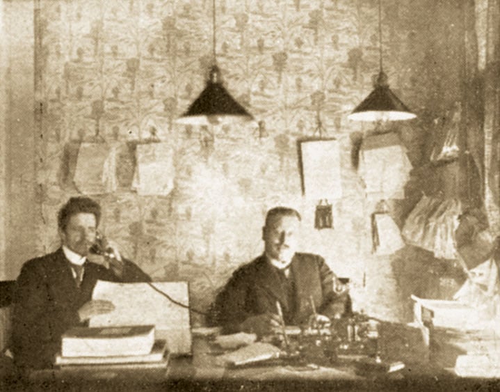 Kaksi miestä vanhanajan konttorissa